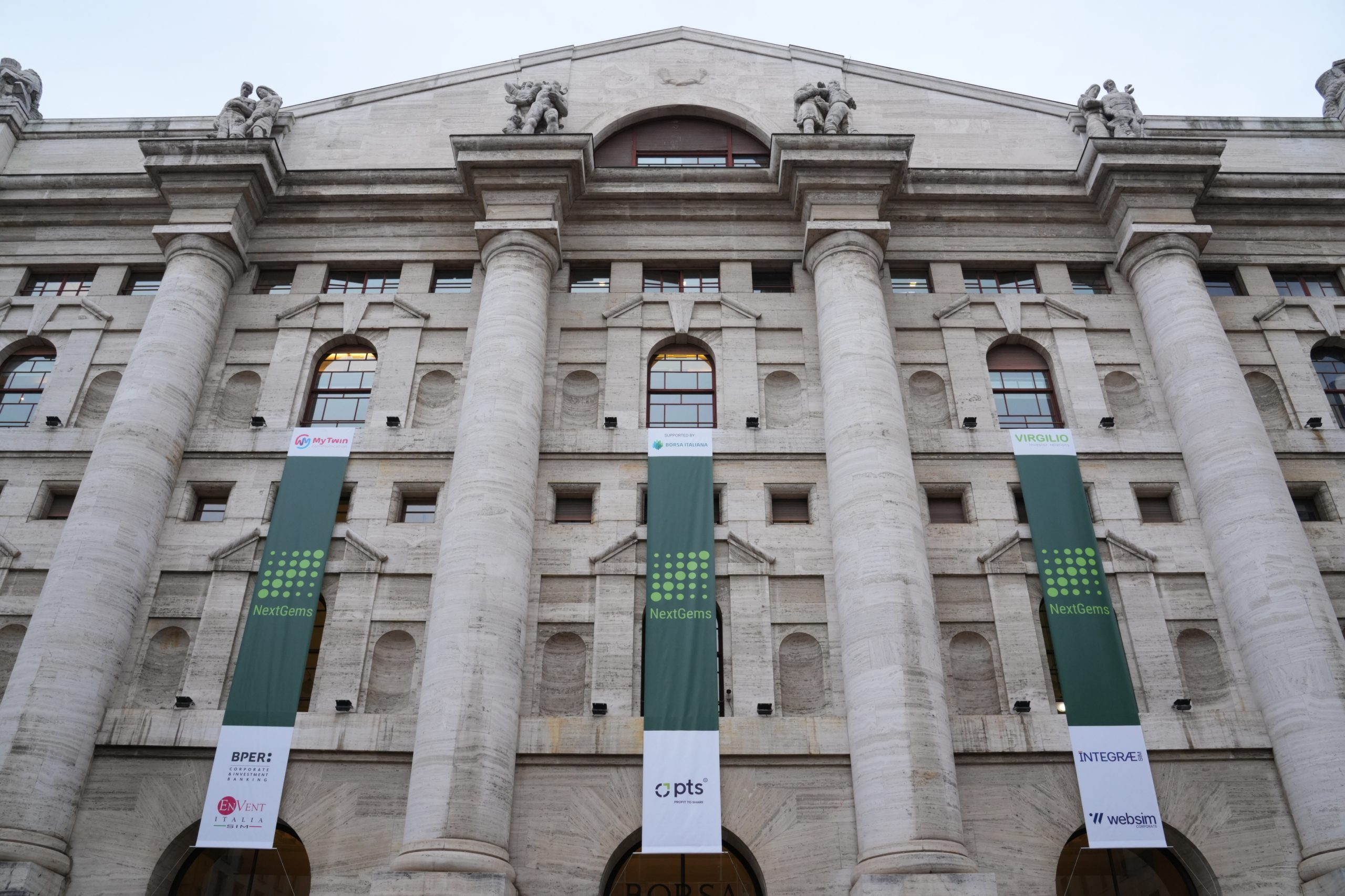 Palazzo Mezzanotte, con vele di NextGems e i loghi dei partner, come My Twin Communication